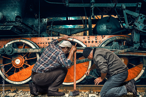 Two mechanics repair an old steam locomotive in a depot © Viktor
