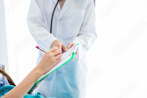 Close-up of female patient Signature for consent form on bed to doctor in the room hospital background.