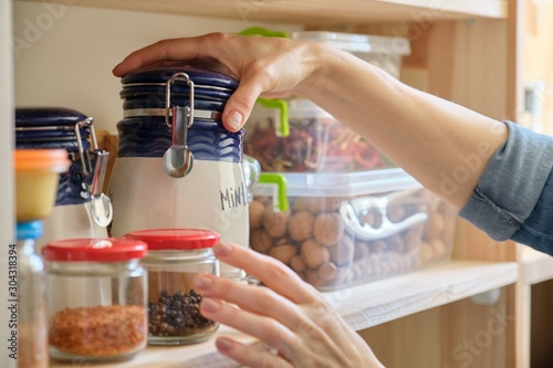 Woman in the kitchen with can of dry mint, food storage, pantry photo