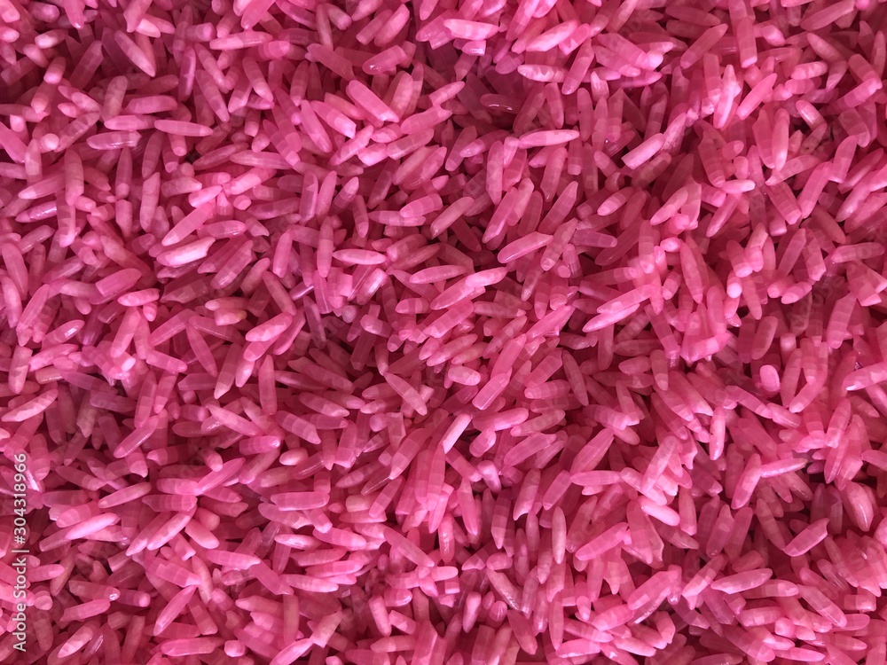 Rice background with granular details, texture. Pink raw uncooked rice close up shot. 