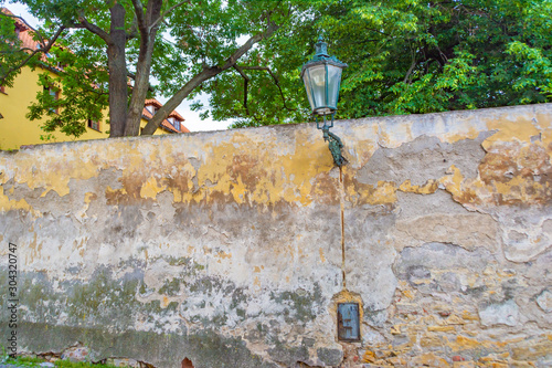 Old wall with peeling paint and a garden with green trees behind it photo