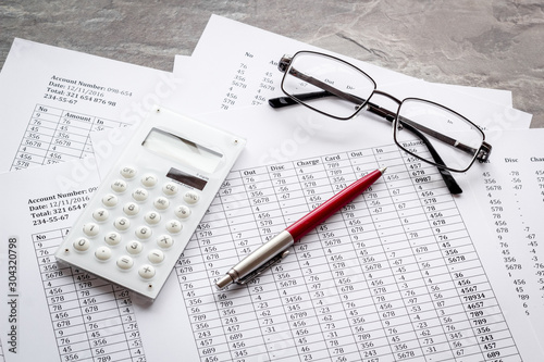 Taxes calculation concept. Financial documents, calculator, glasses on grey background