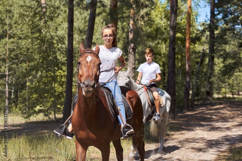 Group of teenagers on horseback riding in summer park