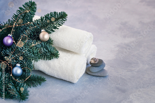Christmas and new year card with fir branches decorated with balls  lights  shells and stones for Spa treatments on a gray background