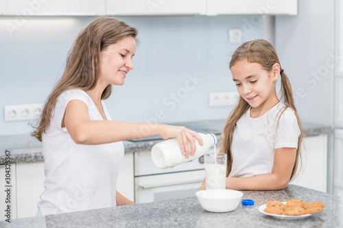 Smiling young woman and her little cute daughter have breakfast at home