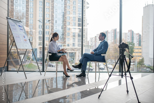 Investor giving the interview to famous journalist sitting near window