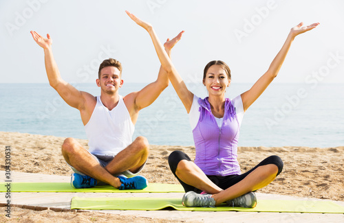 Couple training yoga on beach