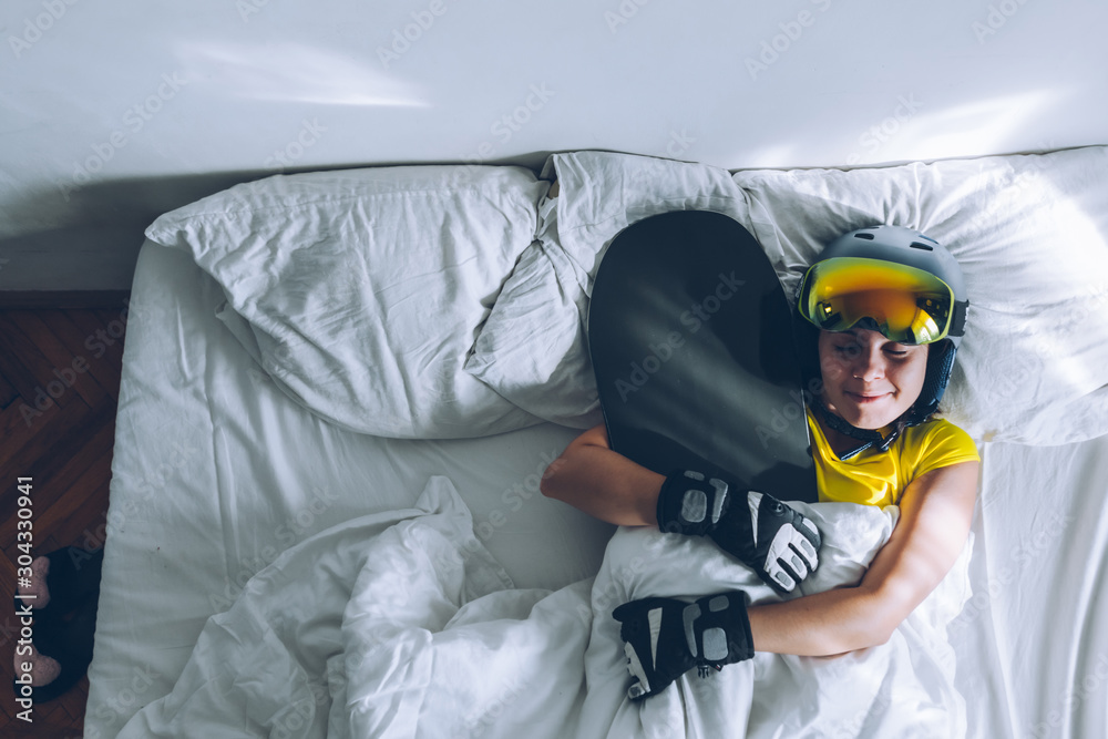 woman sleeping in bed with snowboard dreaming about ski at snow mountains woman sleeping in bed with snowboard dreaming about ski at snow mountains