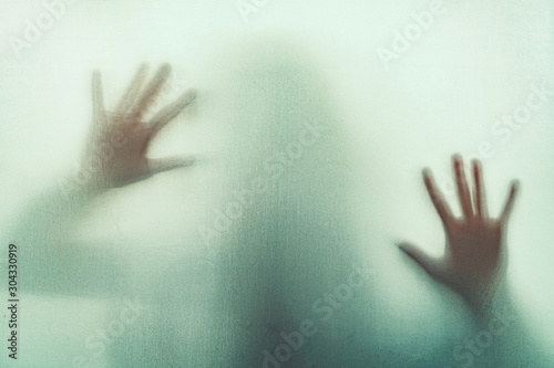 Shadow of scary paranormal ghost horror woman in soft focus. Blurry hand and body figure abstraction.