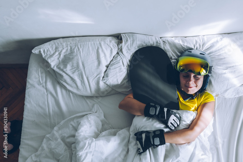 woman sleeping in bed with snowboard dreaming about ski at snow mountains