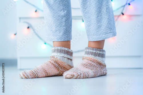 Female legs in warm knitted soft cozy socks in wintertime at home.