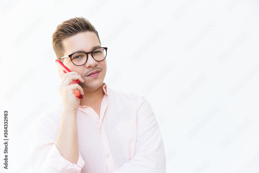 Skeptical guy in eyeglasses speaking on cell and looking at camera. Young man in glasses standing isolated over white background. Phone talk concept Skeptical guy in eyeglasses speaking on cell and looking at camera. Young man in glasses standing isolated over white background. Phone talk concept