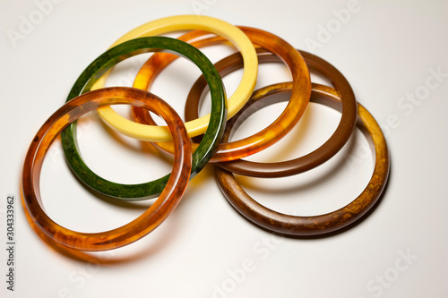 Close up view of vintage bakelite bangle bracelets in varying colors and widths on white background