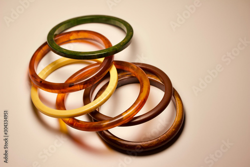 Close up view of vintage bakelite bangle bracelets in varying colors and widths on white background