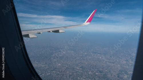 The window of the flying story can see the wings of the plane and the beautiful sky.
