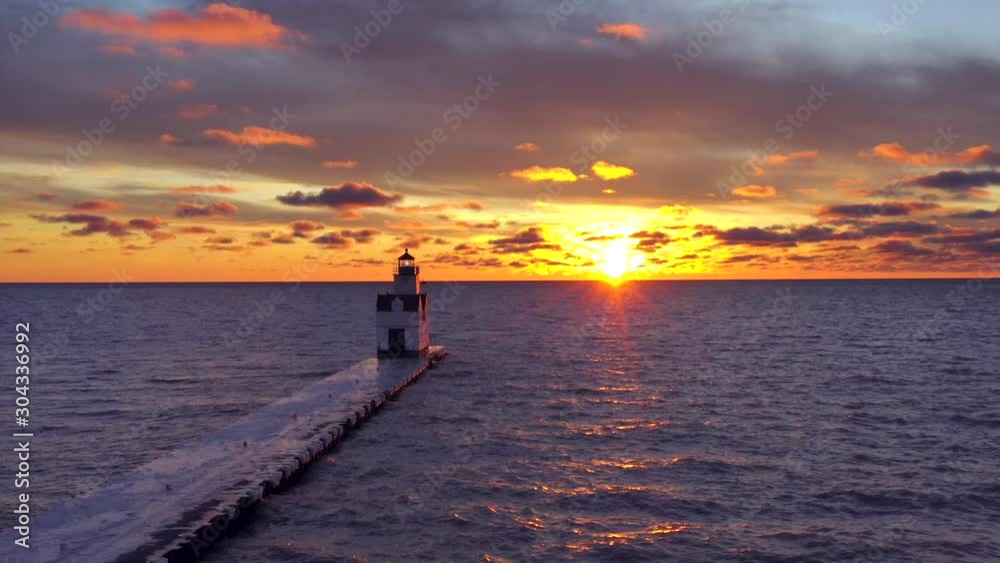 Moving drone aerial view of dramatic sunrise sky with bright but lonely Lighthouse beacon.