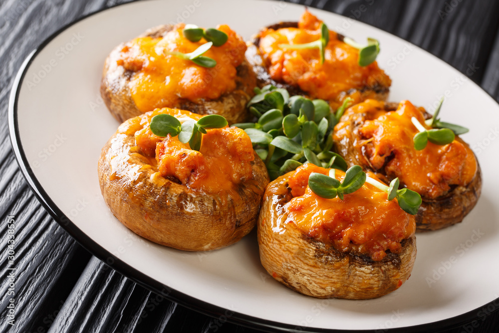 Appetizer of baked mushrooms stuffed with minced meat and cheddar cheese close-up on a plate. horizontal Appetizer of baked mushrooms stuffed with minced meat and cheddar cheese close-up on a plate. horizontal