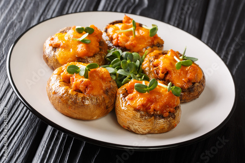 Traditional portobello mushrooms stuffed with minced meat and cheddar cheese close-up on a plate. horizontal