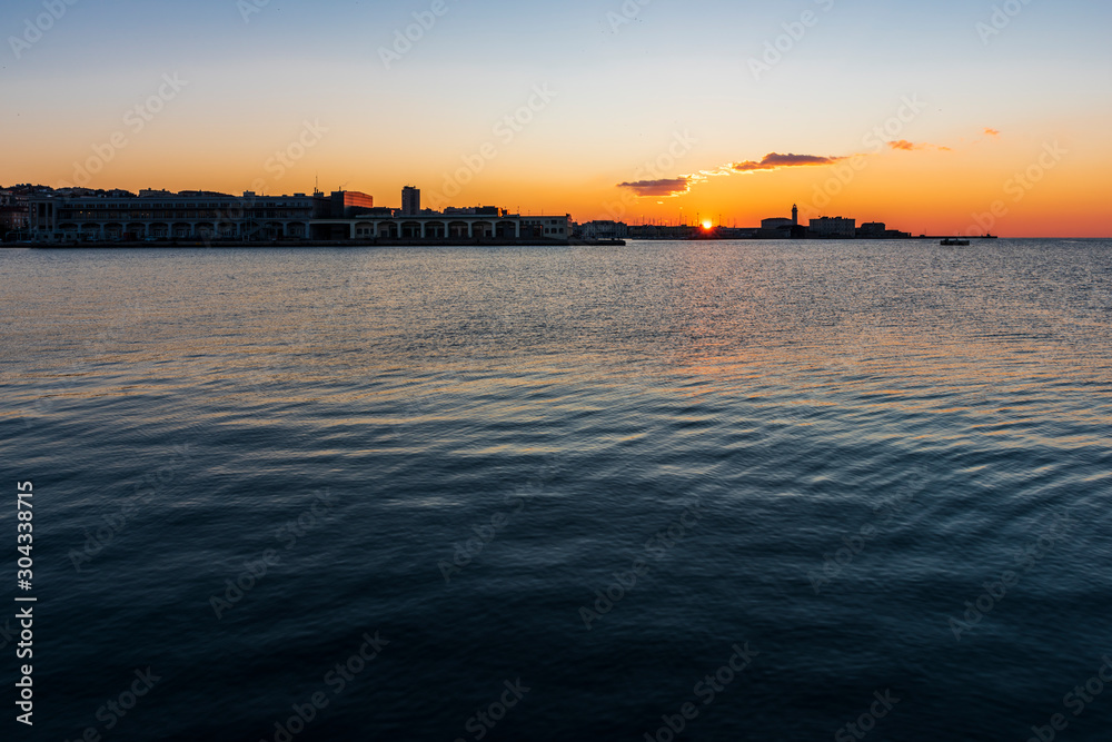 Sunset from the Audace pier of Trieste. Colors of fire on the water. Italy