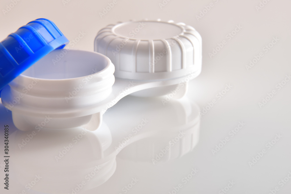 Contact lens case open reflected on white glass table Contact lens case open reflected on white glass table
