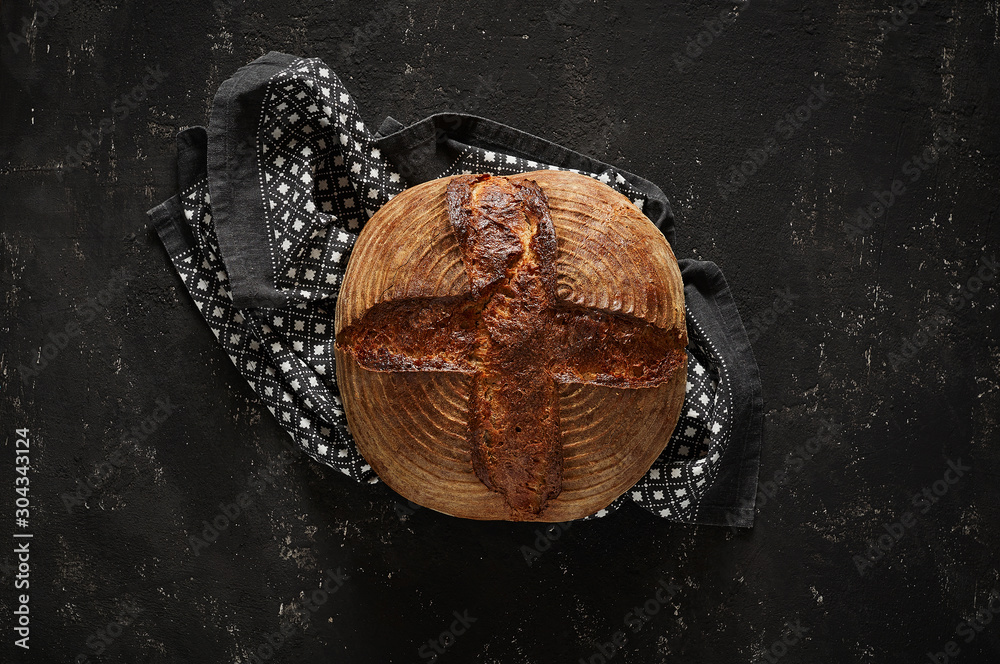 Freshly baked Artisan sourdough bread loaves with kitchen towel on black concrete backgroun