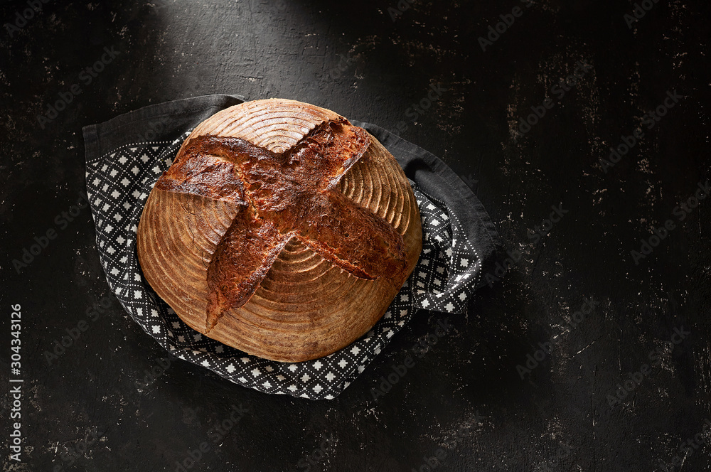 Freshly baked Artisan sourdough bread loaves with kitchen towel on black concrete backgroun
