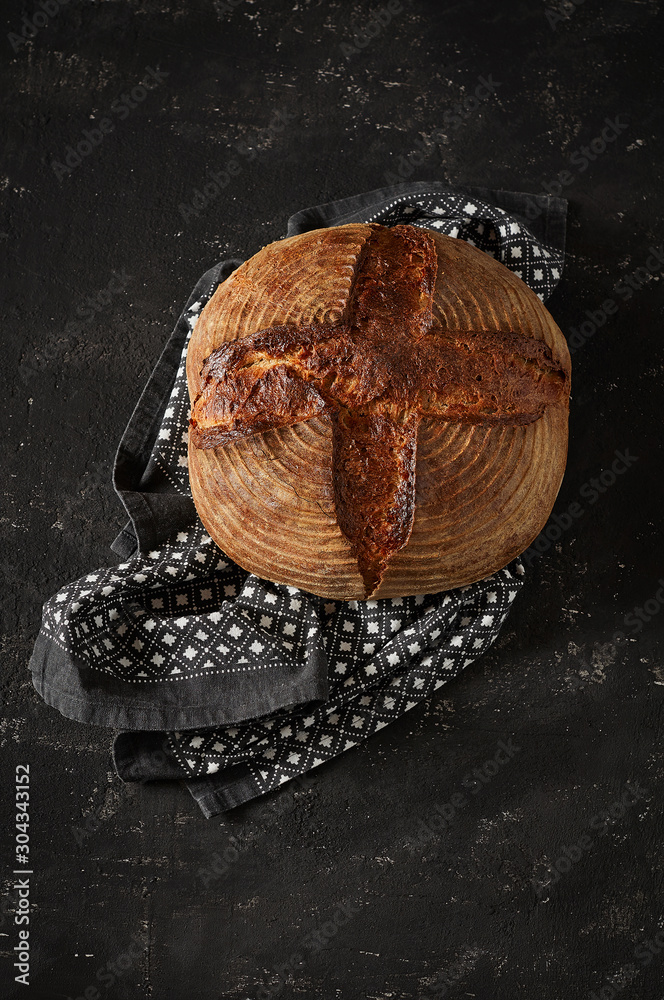 Freshly baked Artisan sourdough bread loaves with kitchen towel on black concrete backgroun