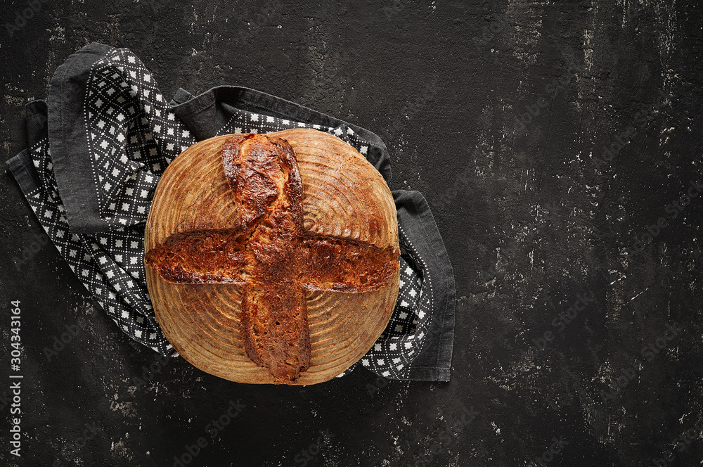 Freshly baked Artisan sourdough bread loaves with kitchen towel on black concrete backgroun