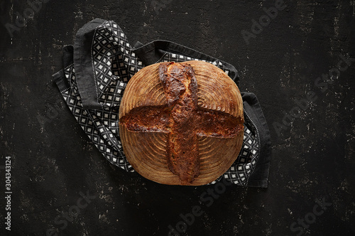 Obraz na płótnie Freshly baked Artisan sourdough bread loaves with kitchen towel on black concrete backgroun w salonie