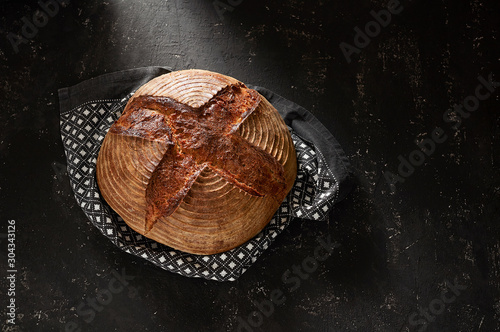 Obraz na płótnie Freshly baked Artisan sourdough bread loaves with kitchen towel on black concrete backgroun w salonie