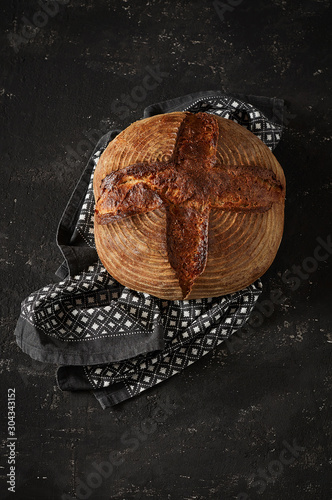 Obraz na płótnie Freshly baked Artisan sourdough bread loaves with kitchen towel on black concrete backgroun w salonie
