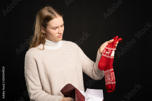 disappointed young woman holds up her gift socks