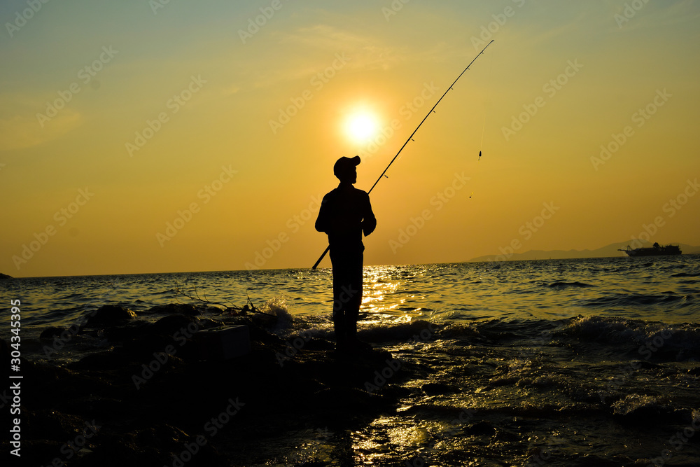 fisherman silhouette with sunset and sea scenery