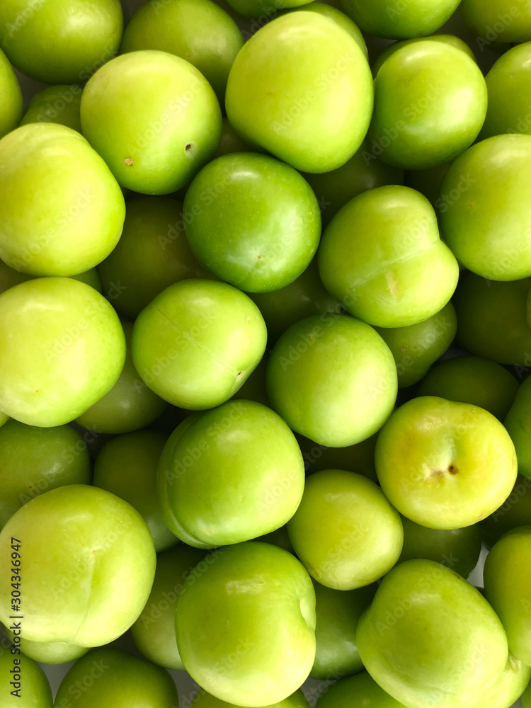 Food background. Top view of a bunch of green cherry plum. Vertical, close-up, cropped shot. Concept of healthy eating.