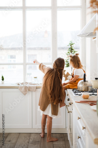 Two sisters play in a bright, stylish kitchen. Beautiful interior.