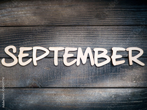 The name of the month is composed of light wooden letters on dark wood. The month of September. 