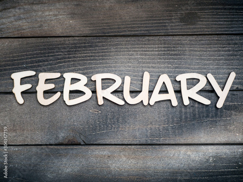 The name of the month is composed of light wooden letters on dark wood. The month of February. 