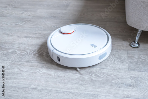Robotic vacuum cleaner on the floor cleaning the room. Smart cleaning technology.
