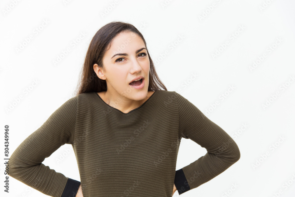 Angry suspicious woman keeping hand on hips and shouting at camera. Young woman in casual standing isolated over white background. Negative emotion or conflict concept Angry suspicious woman keeping hand on hips and shouting at camera. Young woman in casual standing isolated over white background. Negative emotion or conflict concept
