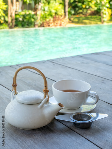 Afternoon tea with white kettle and cup side of pool with natural light