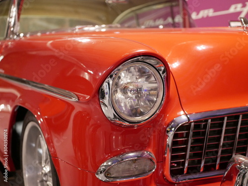 Right headlight head light bright red vintage polished car standing in the garage. © Vladimir Kazachkov