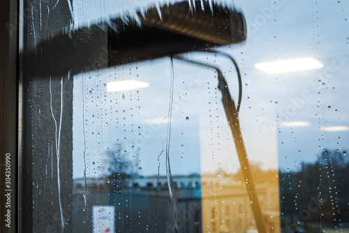 Window cleaning using telescopic water brush and wash system. Commercial window cleaning from the outside with sky in background 
