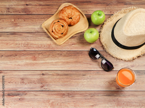 Top view of breakfast set,  pastry , orange juice and apple with hat and sunglasses