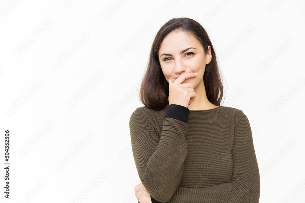 Joyful Latin woman covering mouth with hand and hiding smile. Young woman in casual standing isolated over white background. Keeping silence concept