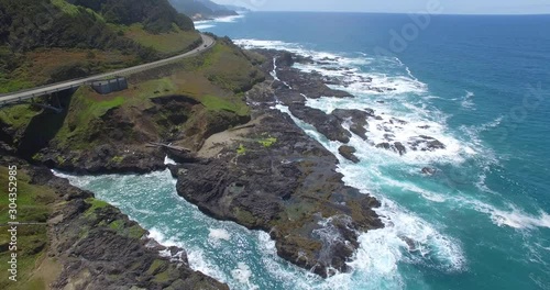 A slow descending aerial perspective of Oregon’s coastline as a vacationing truck vehicle drives down a coastal highway on a Pacific Ocean vacation where many tourists explore the PWN coast.