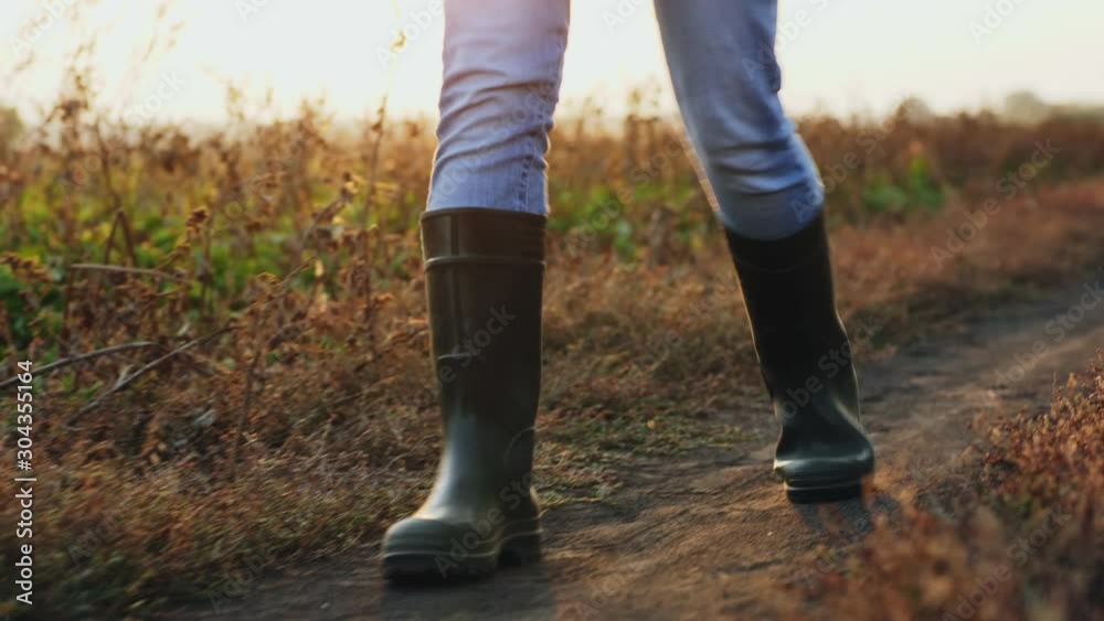 Front view: Man in rubber boots walking down a country road, close-up of legs, slow-motion 4k shot Front view: Man in rubber boots walking down a country road, close-up of legs, slow-motion 4k shot