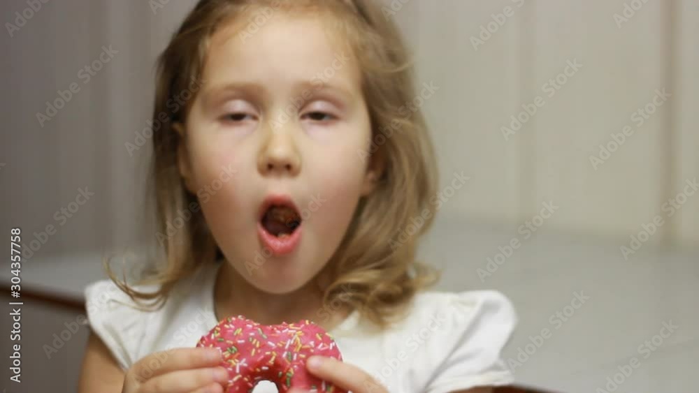 Child mouth bites rose donut. Closeup baby girl eating doughnut with glase. Delicious, sweet, sweettooth Child mouth bites rose donut. Closeup baby girl eating doughnut with glase. Delicious, sweet, sweettooth