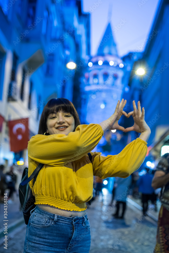 Beautiful woman makes heart shape in front of Galata tower