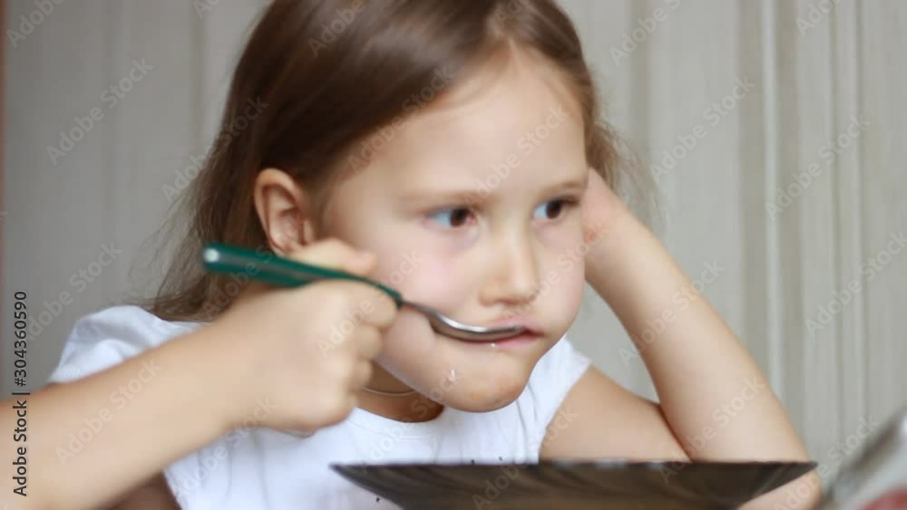 Child eats soup with a spoon. Closeup baby girl sitting at the table of home cooking and eating food. Child eats soup with a spoon. Closeup baby girl sitting at the table of home cooking and eating food.
