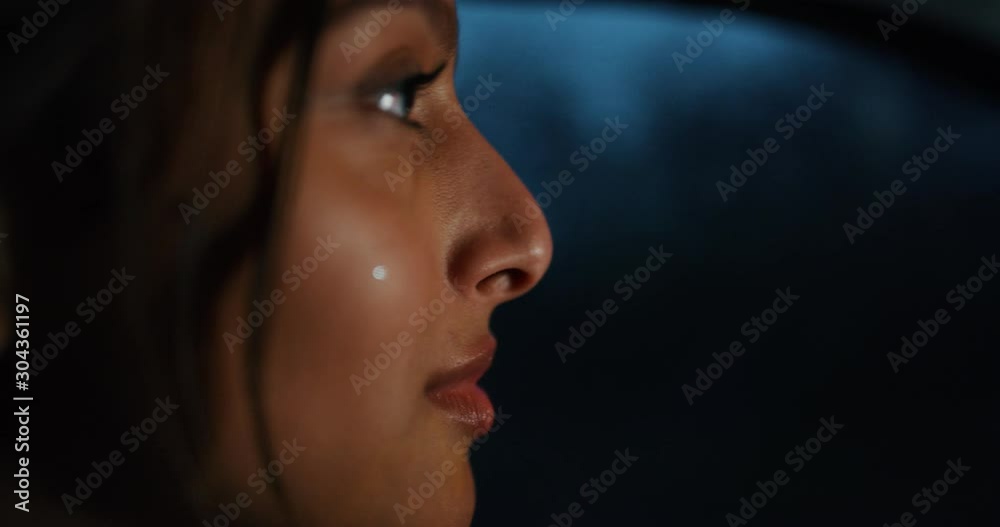 Close up of an young businesswoman is driving a modern car in a center of the city by night while is raining outside. Close up of an young businesswoman is driving a modern car in a center of the city by night while is raining outside.